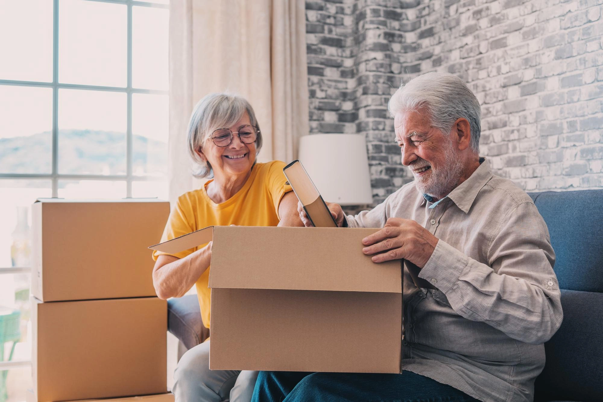 Relaxed mature married couple holding Cardboard boxes