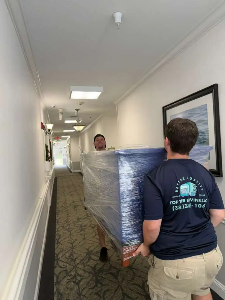 Movers carrying wrapped furniture.